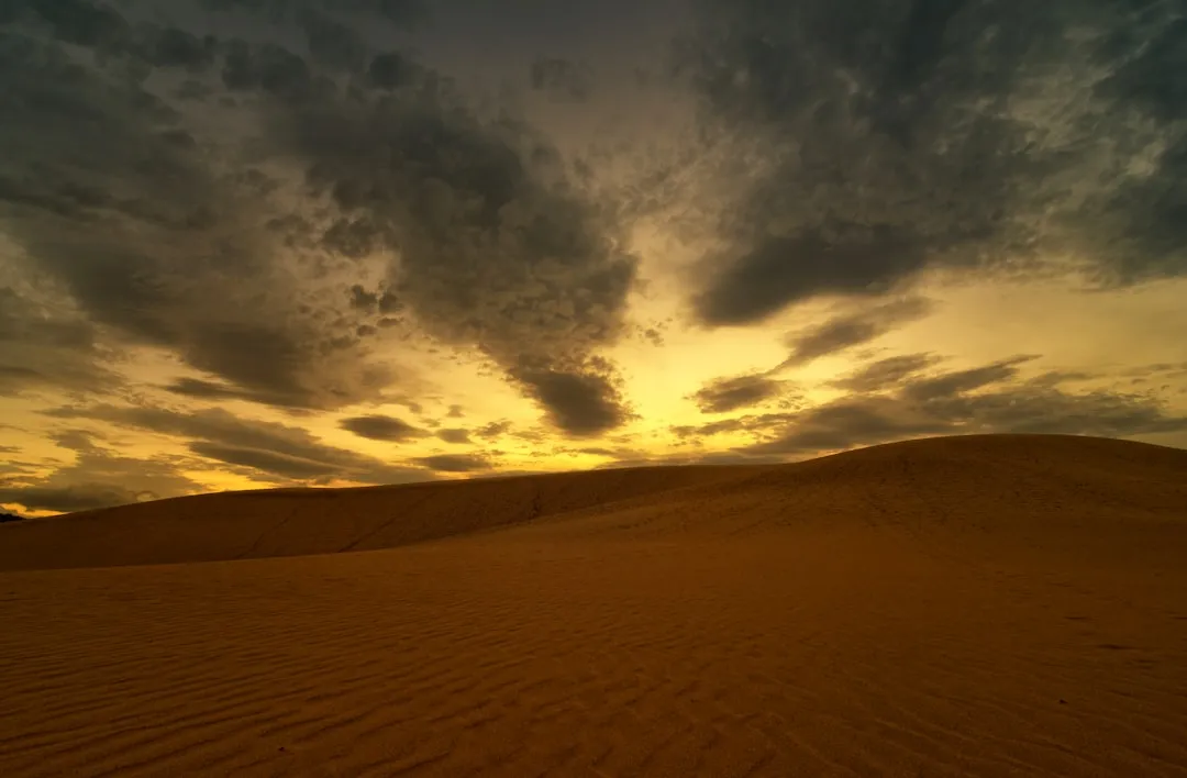 brown sand under blue sky and white clouds during daytime