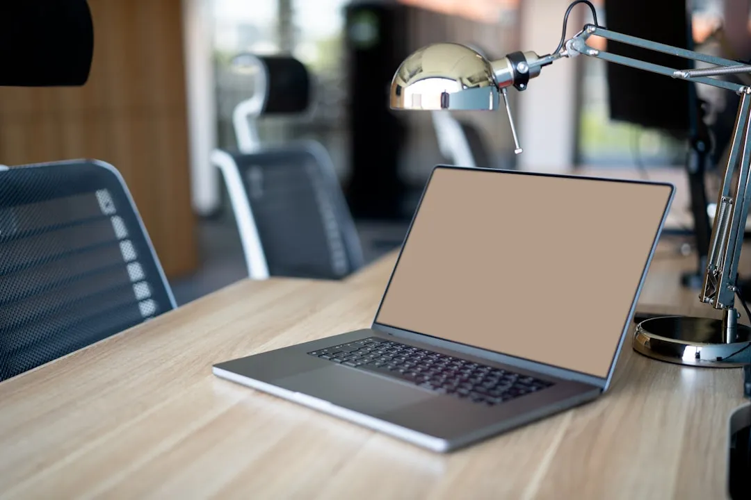 A laptop computer sitting on top of a wooden desk in a conference room