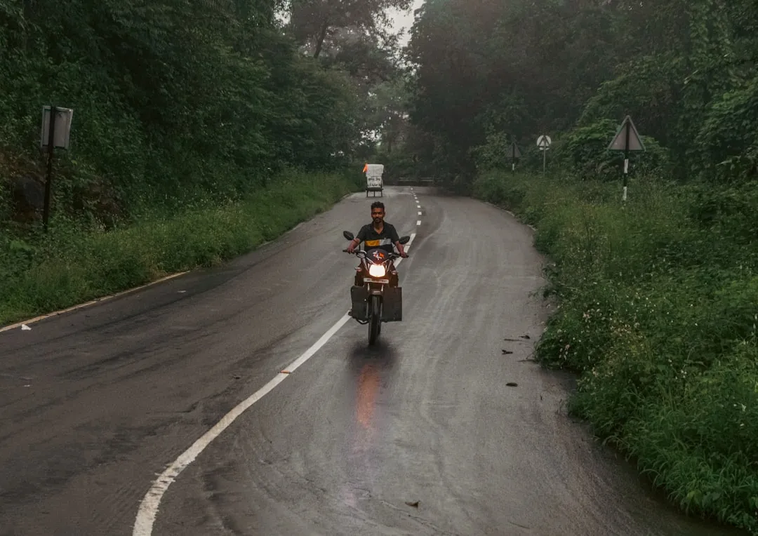 Man riding motorcycle on wet forest road