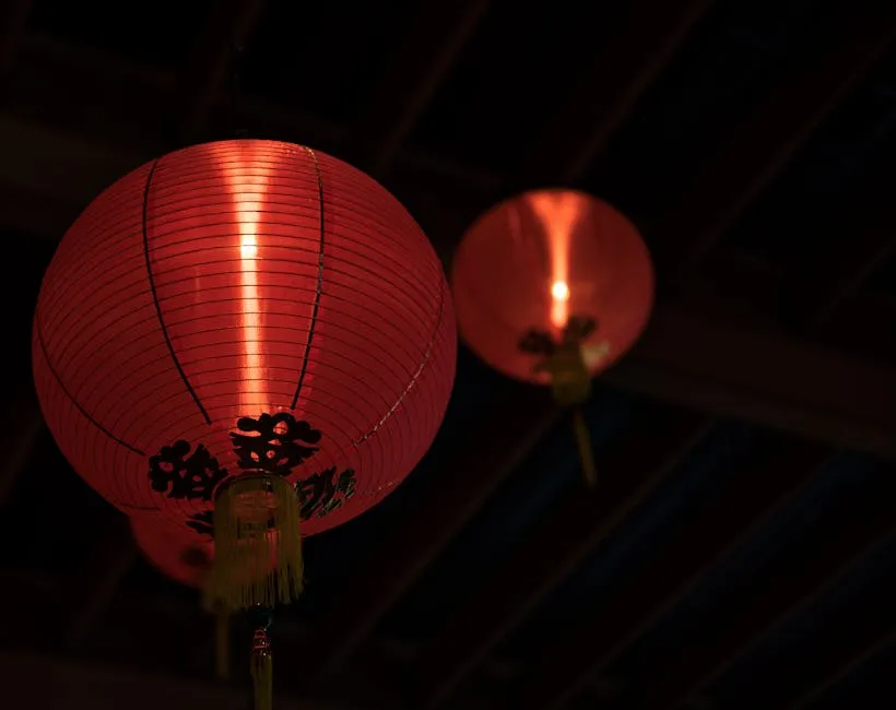 Traditional red Chinese lanterns hanging indoors, glowing warmly.